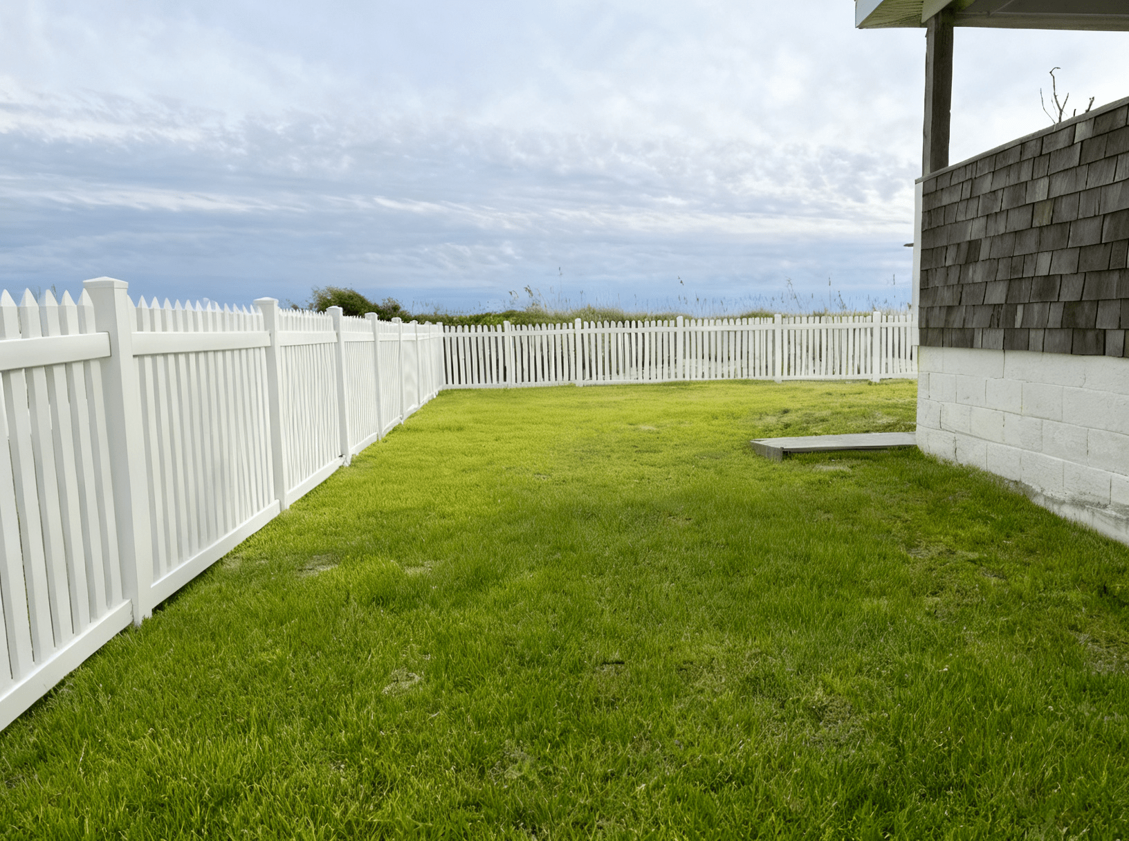 White picket fence around grassy yard.