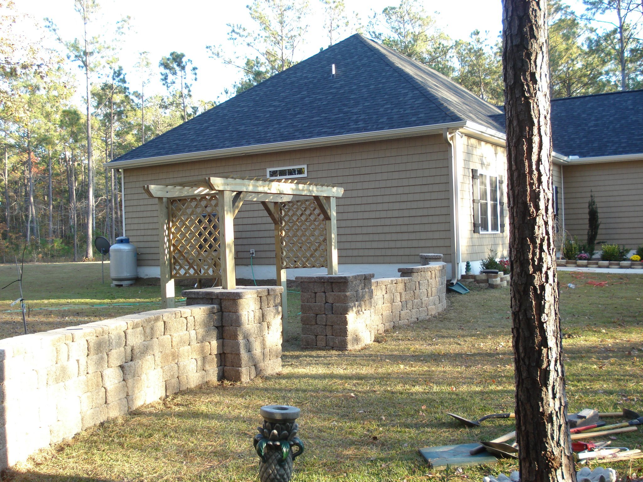 Backyard with brick walls and wooden pergola.