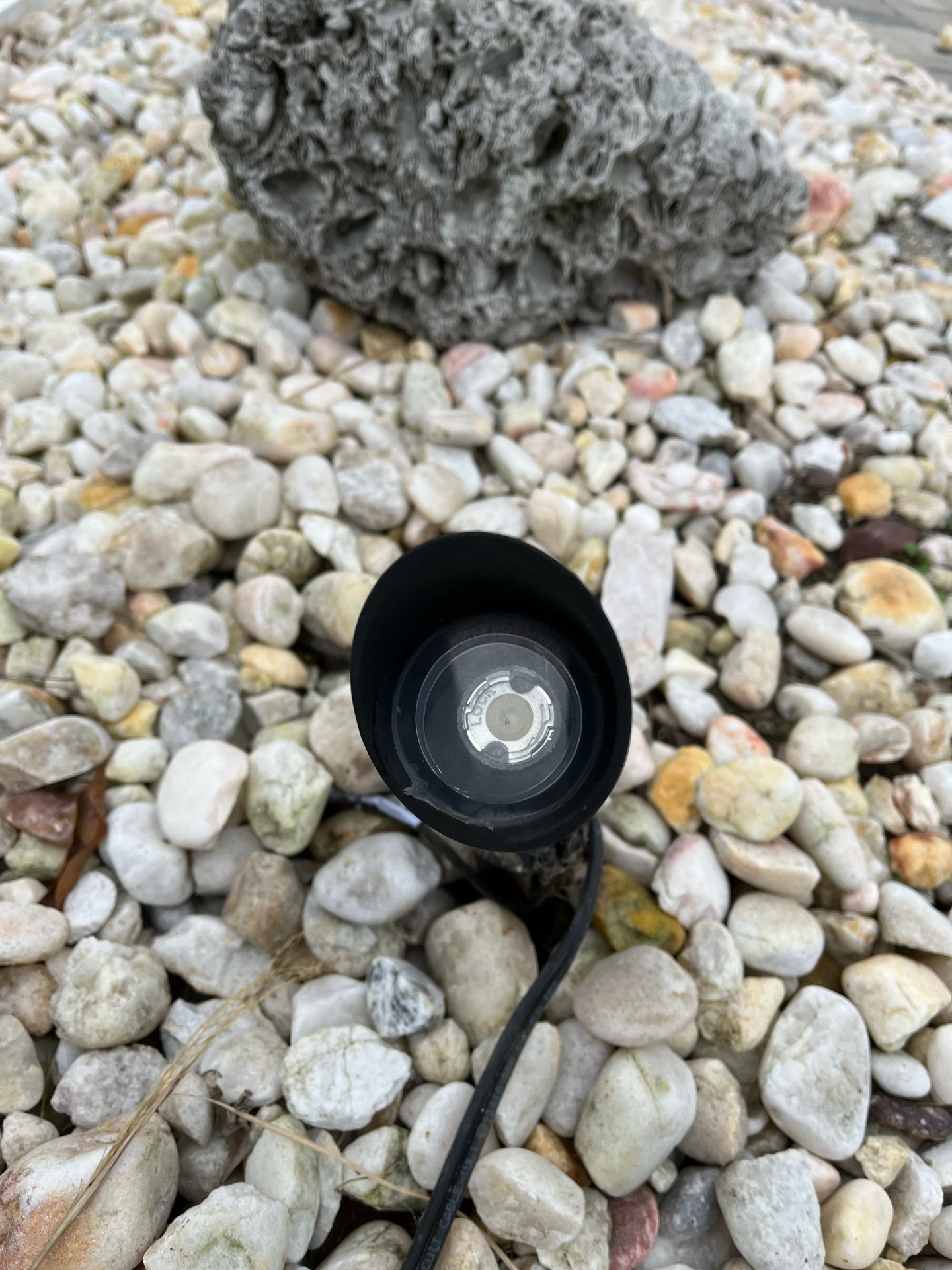 Outdoor spotlight on rocky textured ground.