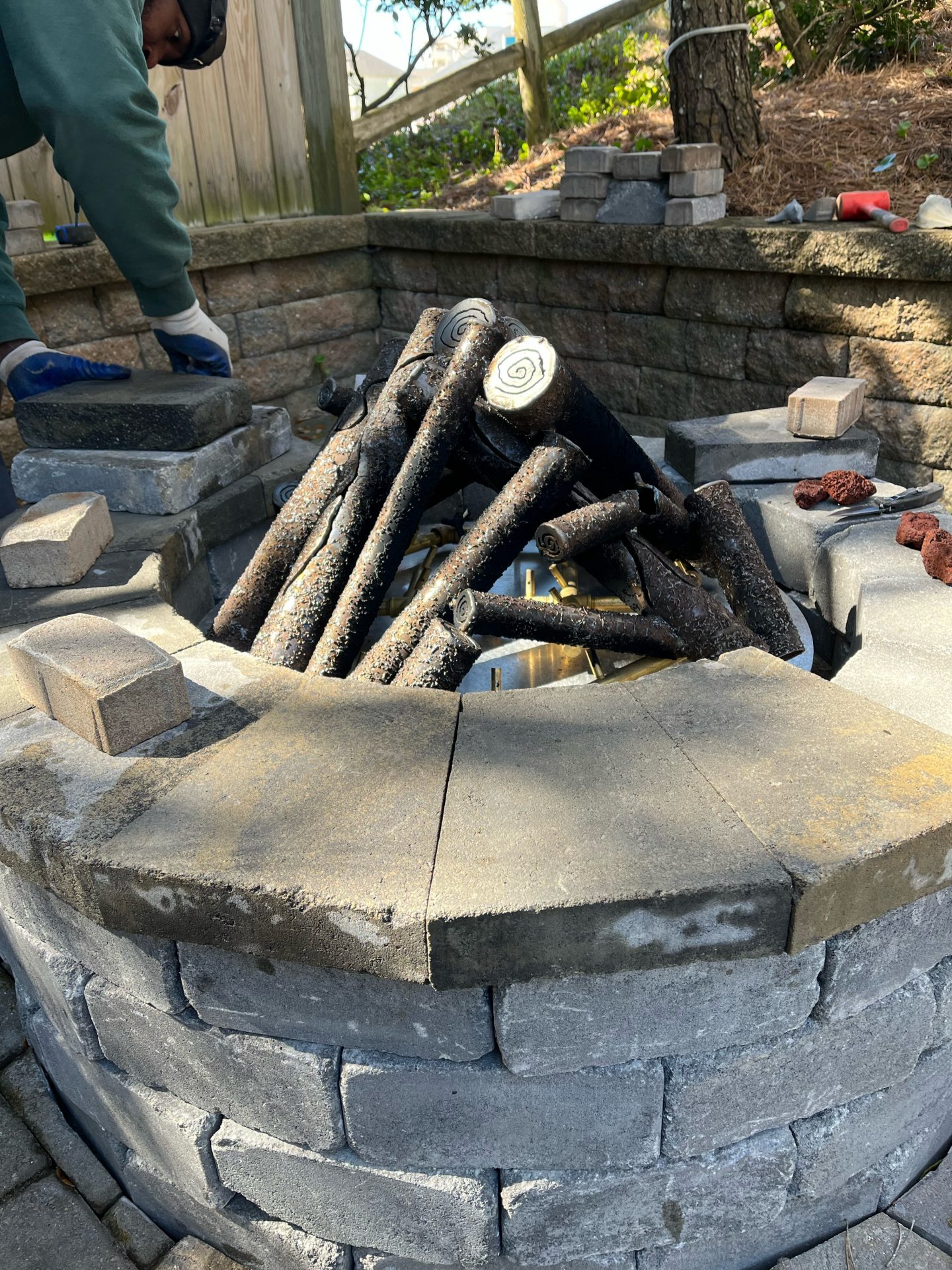 Person building a stone fire pit outdoors.