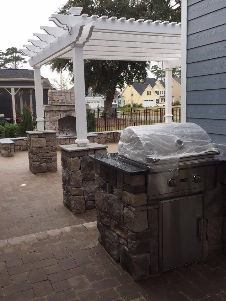 Outdoor patio with grill and pergola.