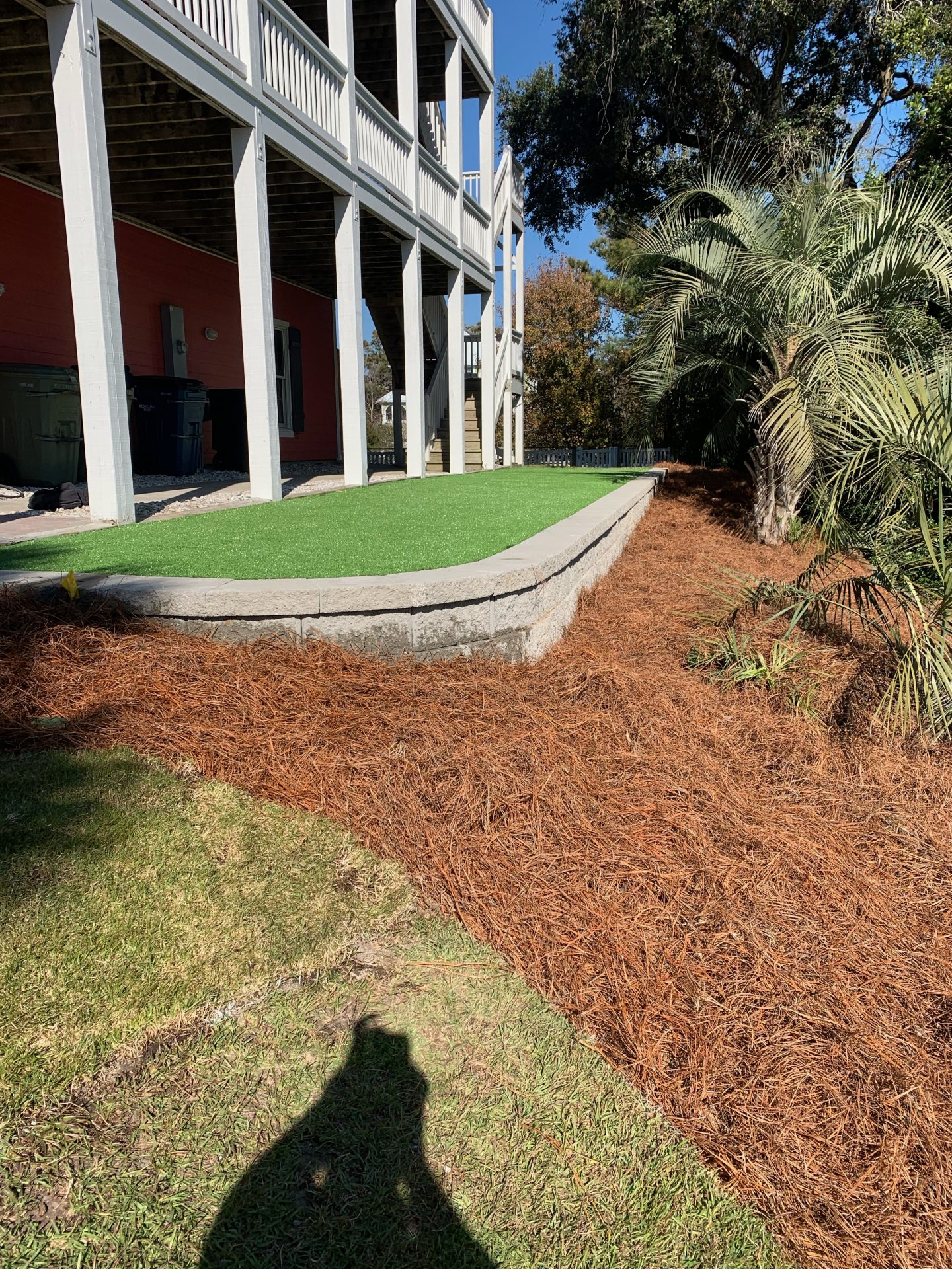 Elevated porch with artificial grass and pine straw