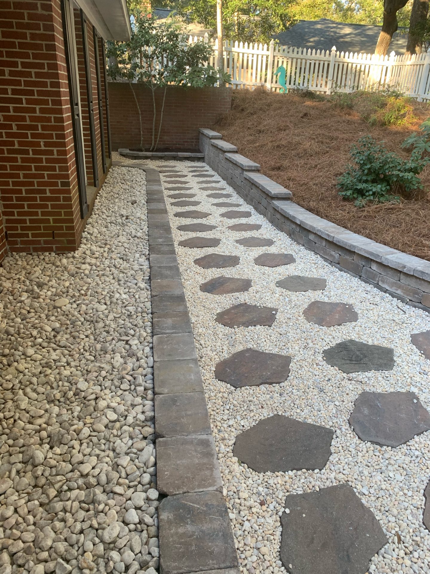 Stone pathway with brick border in backyard.