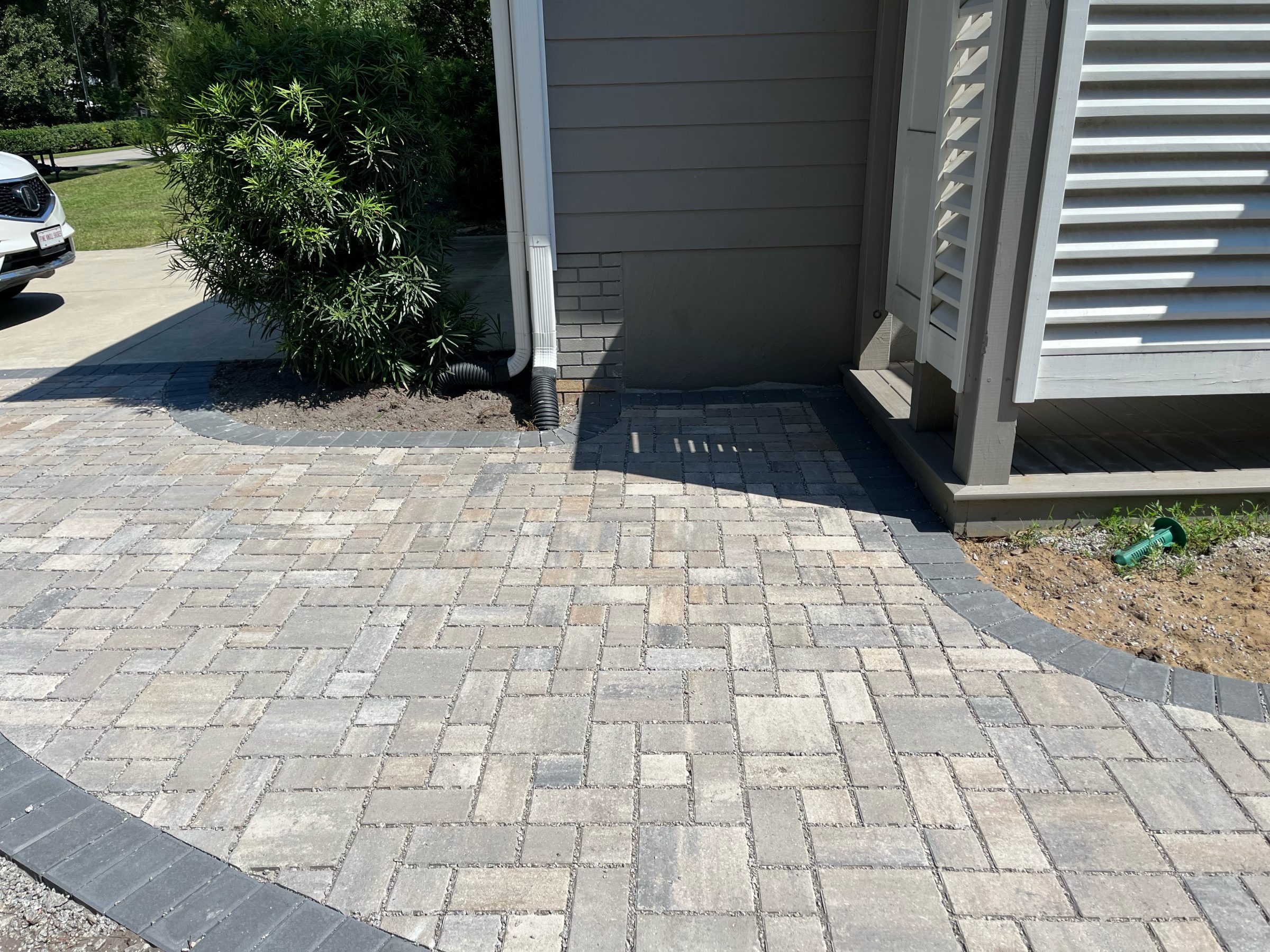 Newly installed brick patio beside house and plants.