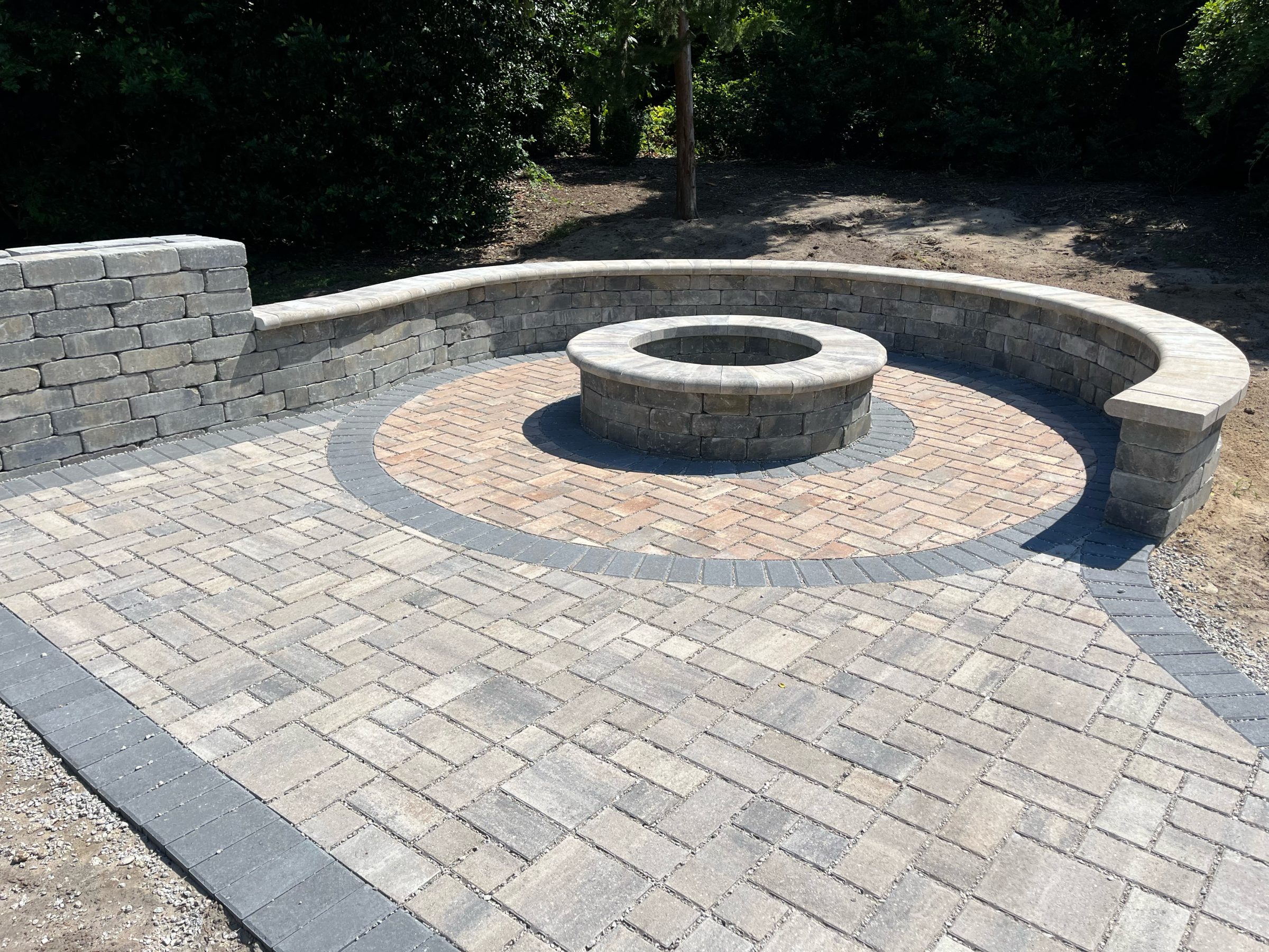 Stone patio with circular fire pit and seating wall.