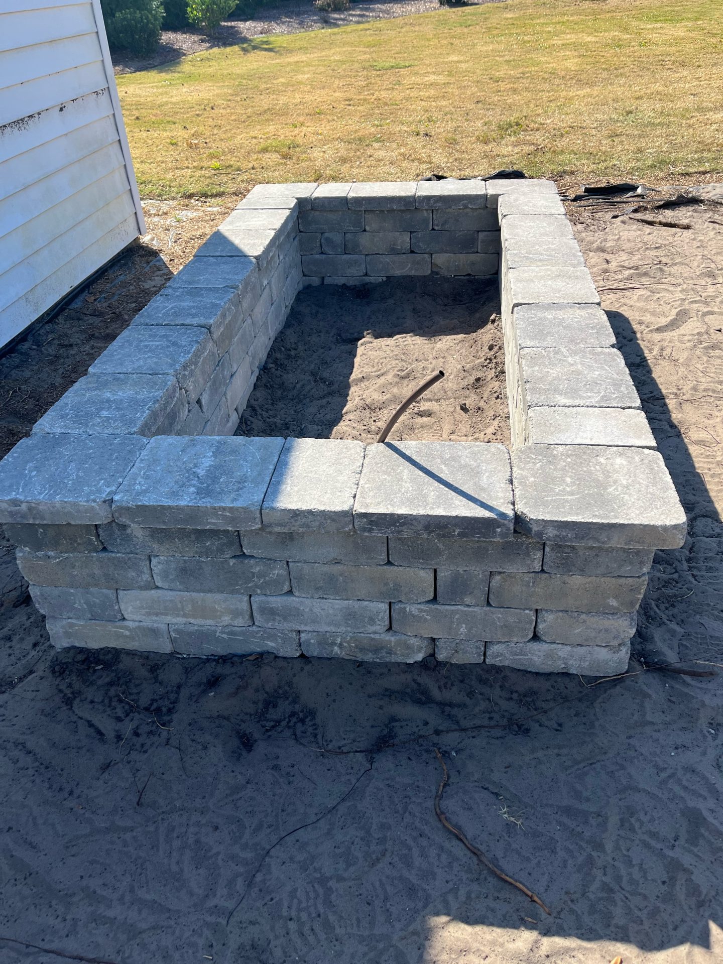Stone planter box under construction in backyard.