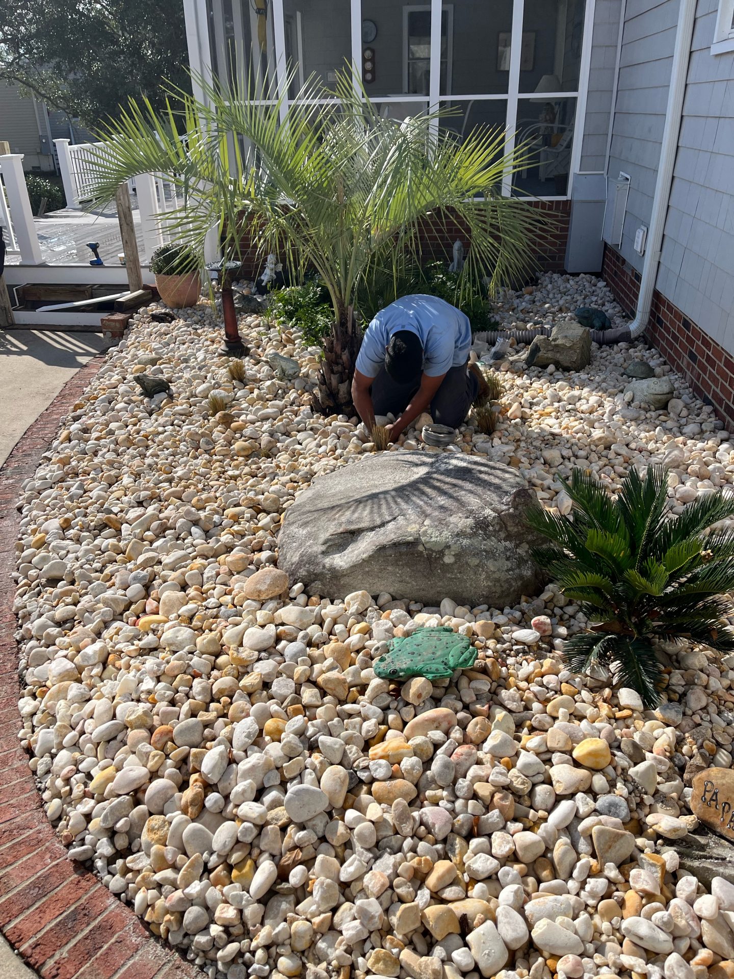 Gardener planting in a stone-covered garden area.