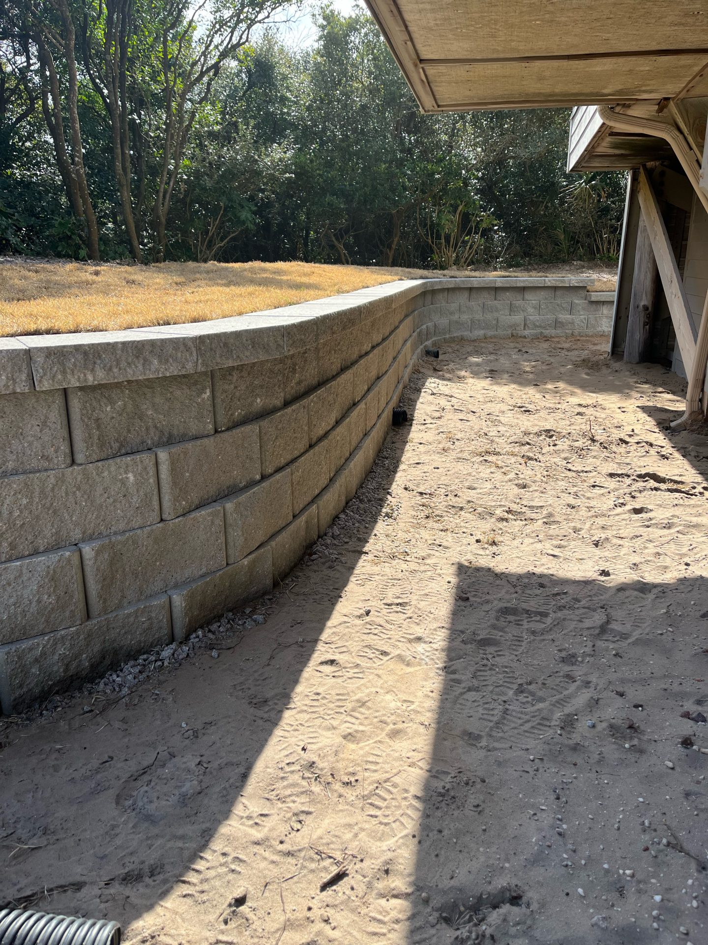 Curved retaining wall with sandy pathway below.