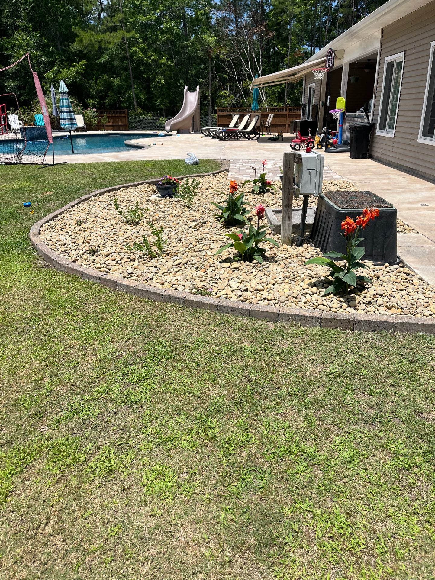 Backyard pool with flower garden and slide.