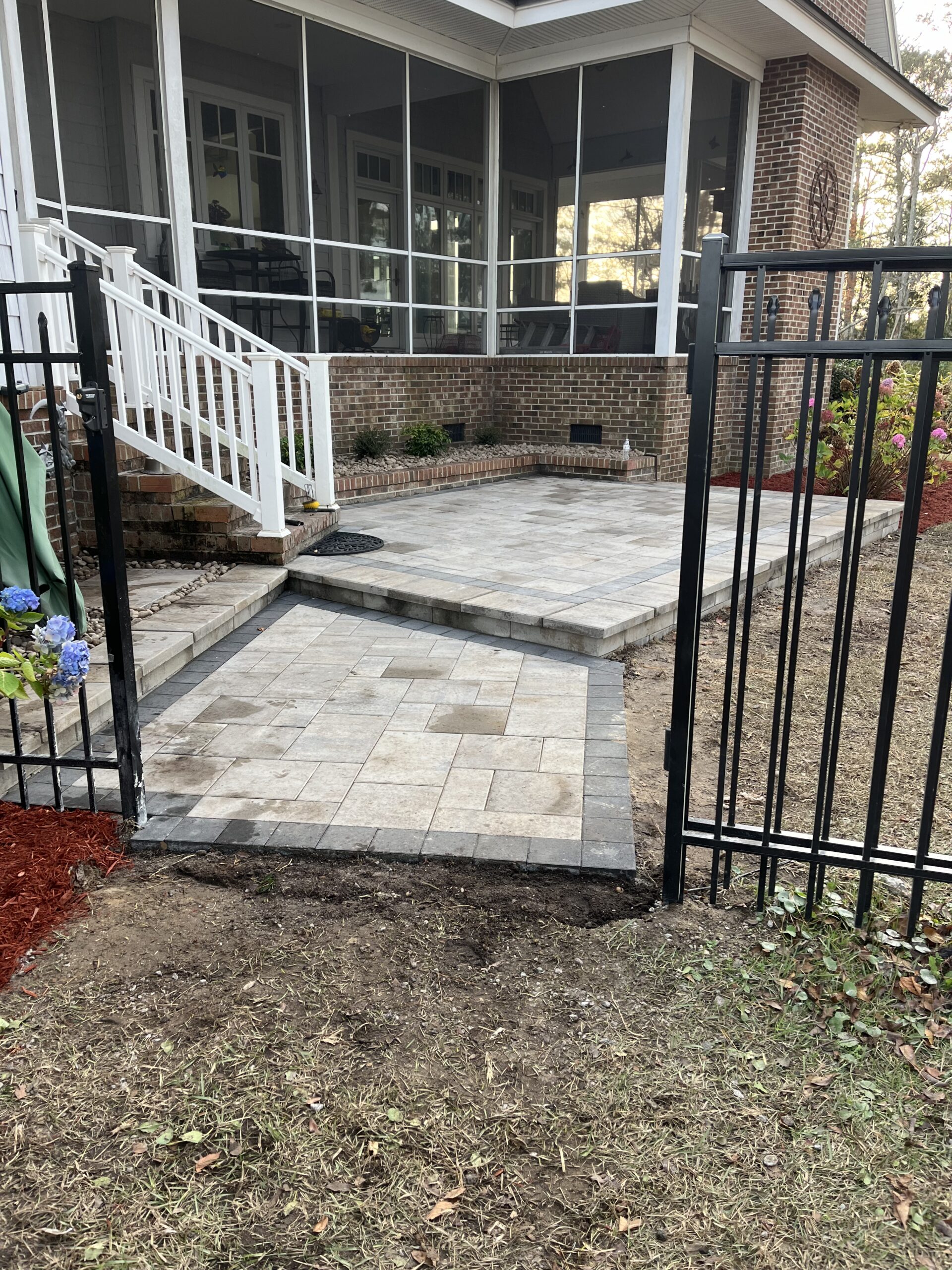 Brick patio with white railing and black fence