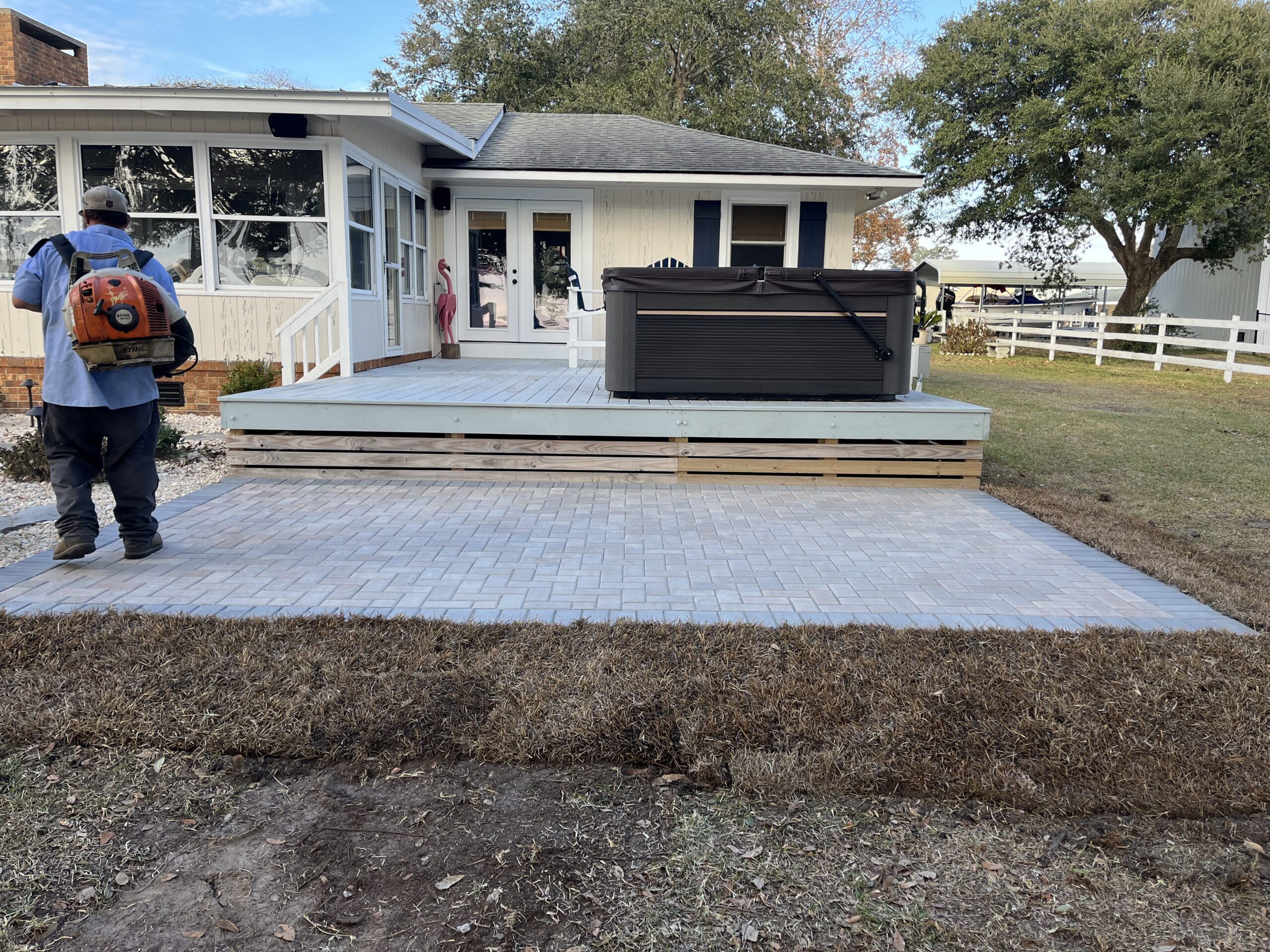 Backyard patio with hot tub and worker.
