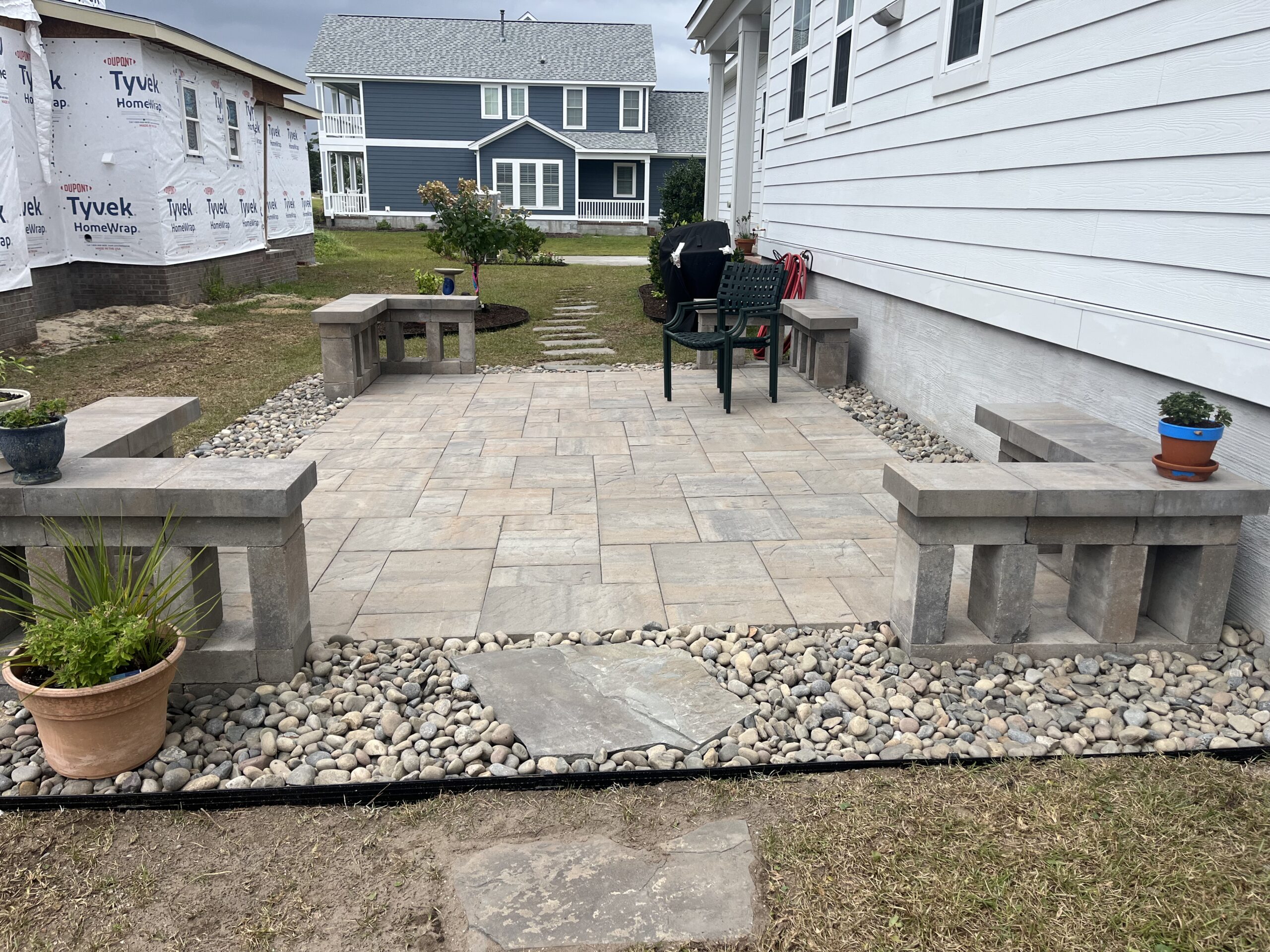 Backyard patio with stone benches and plants.
