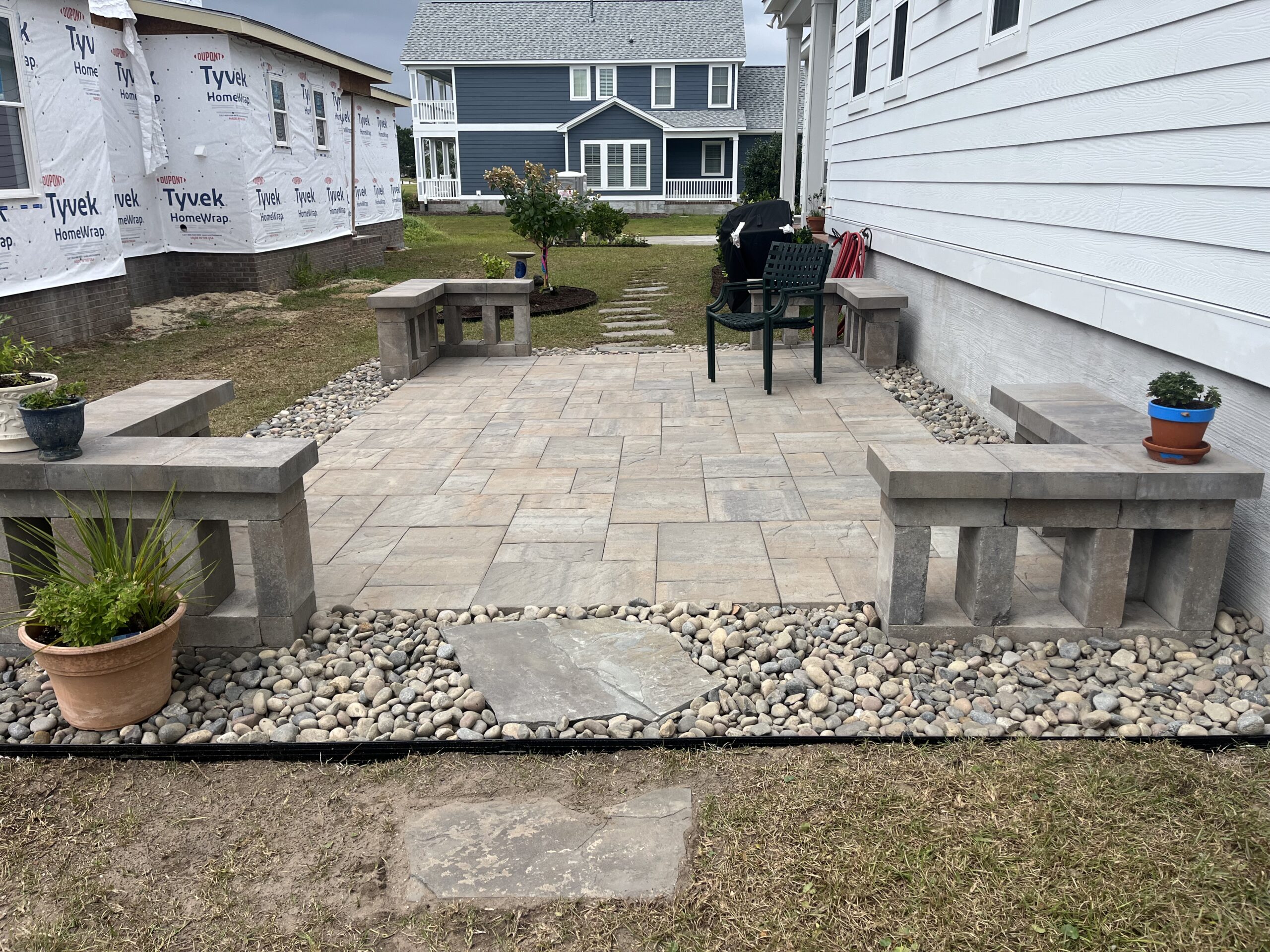 Stone patio with benches and potted plants.