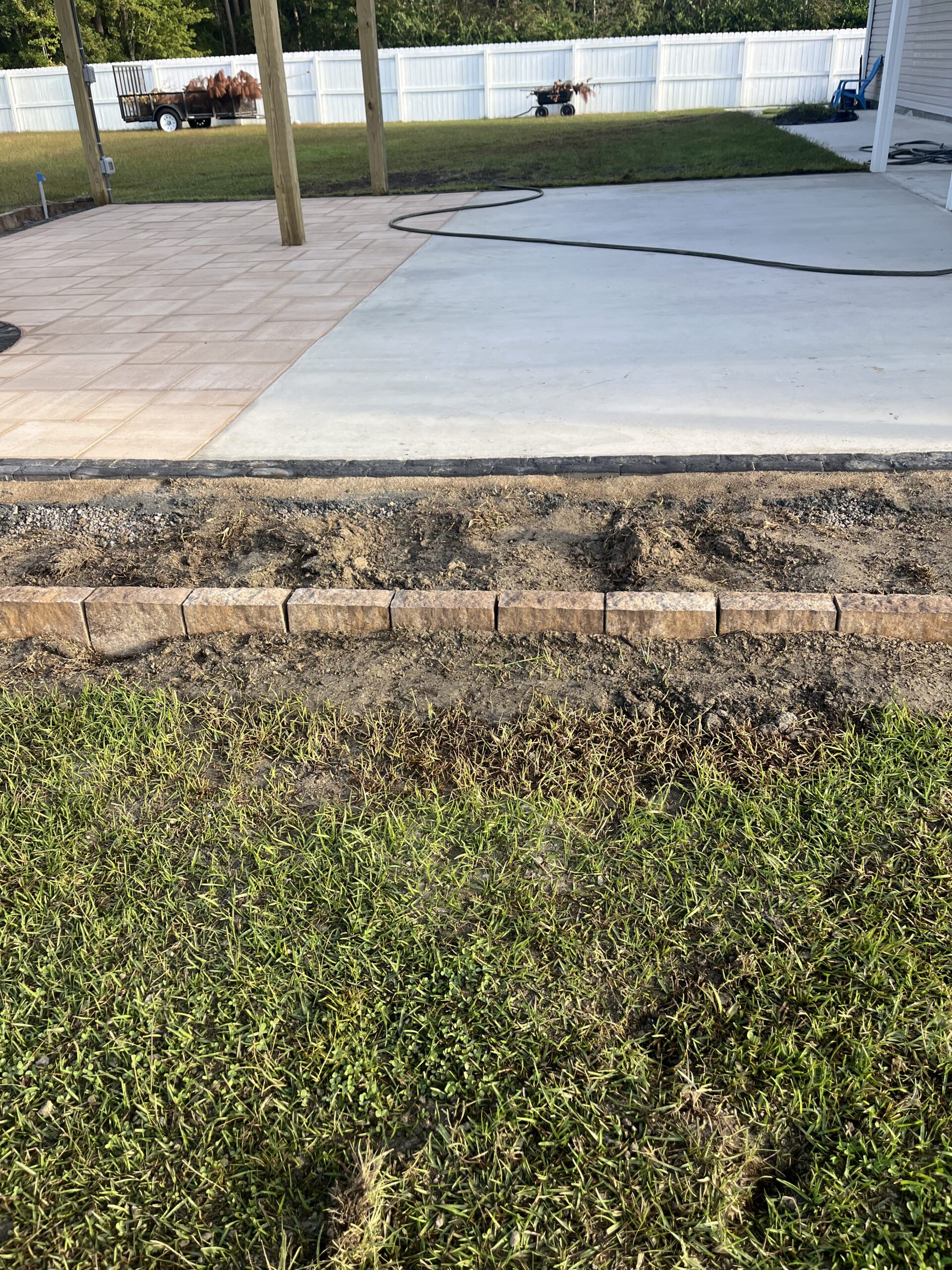 Backyard patio with grass and fence.
