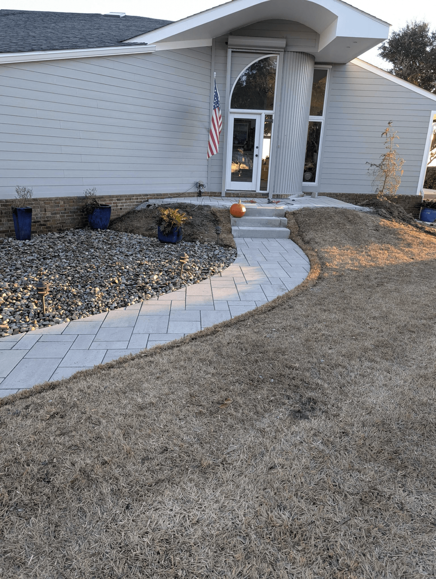 House with lawn, pathway, American flag, and pumpkin.