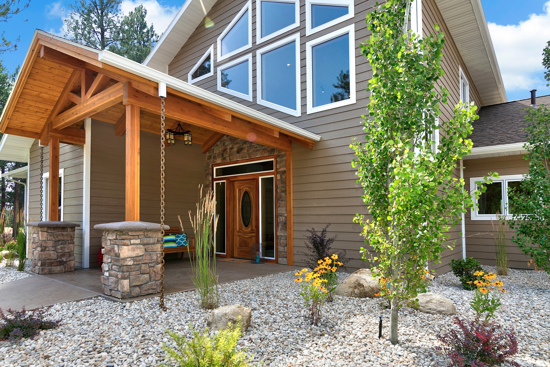 Modern house entrance with stone columns and landscaping.