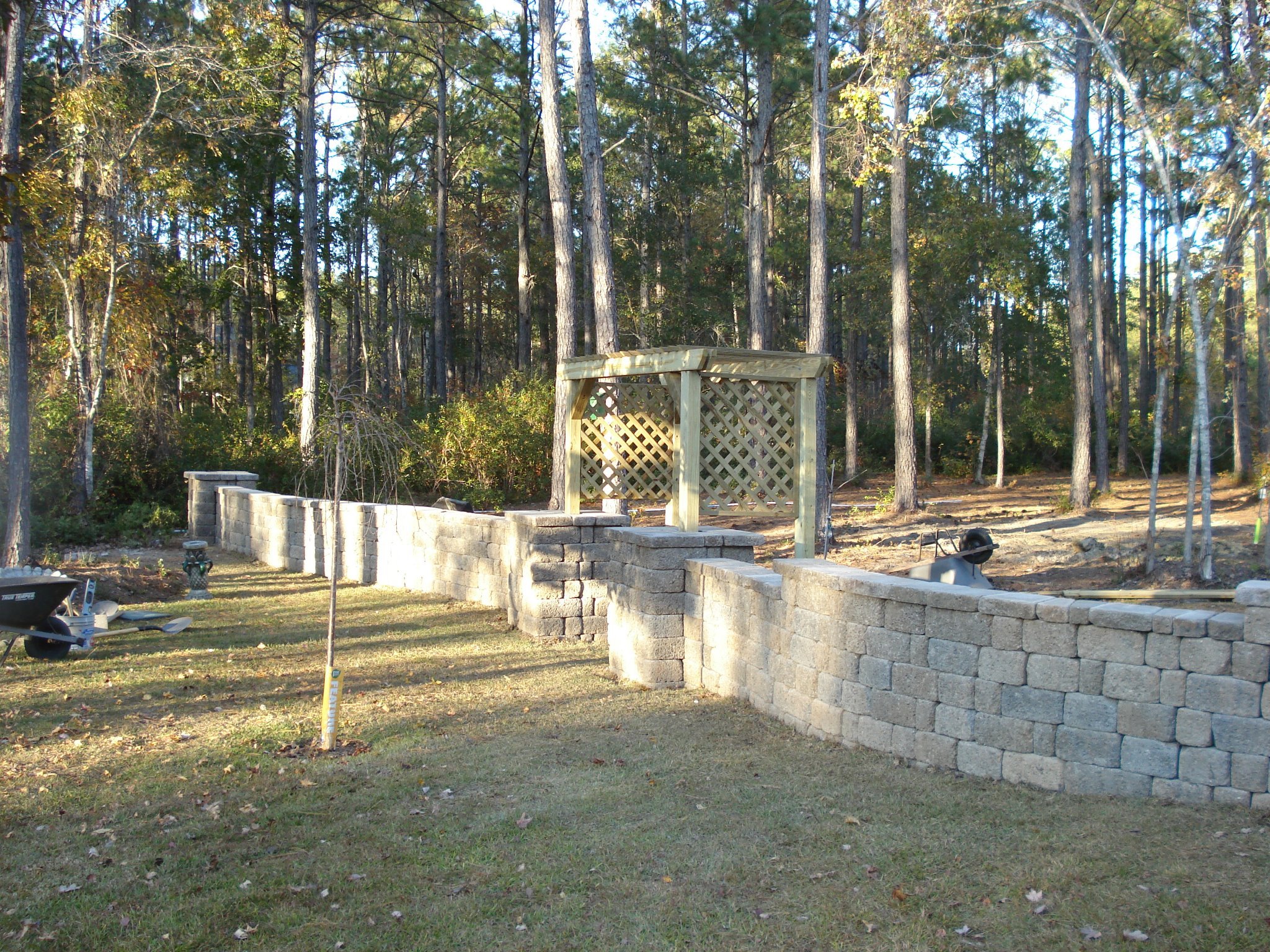 Stone garden wall with wooden arbor in forest